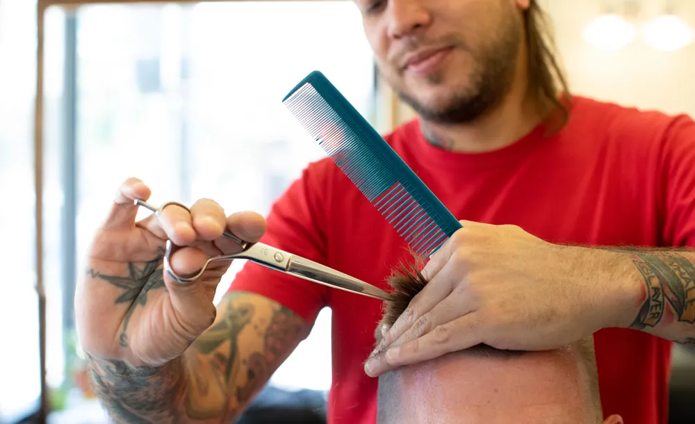 Close-up of a barber cutting with scissors and comb