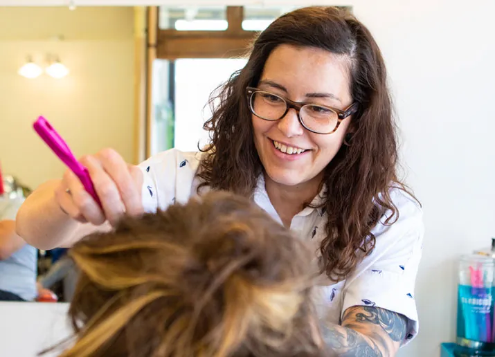 Genevieve smiling while styling a client's hair