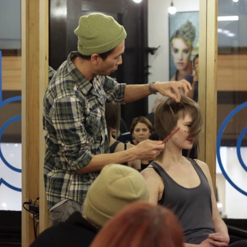 Ken cutting a client's hair in front of a mirror